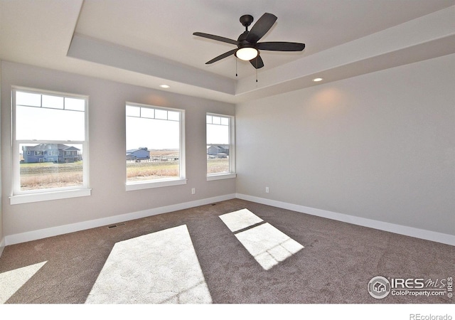 spare room with a tray ceiling, carpet, ceiling fan, baseboards, and recessed lighting