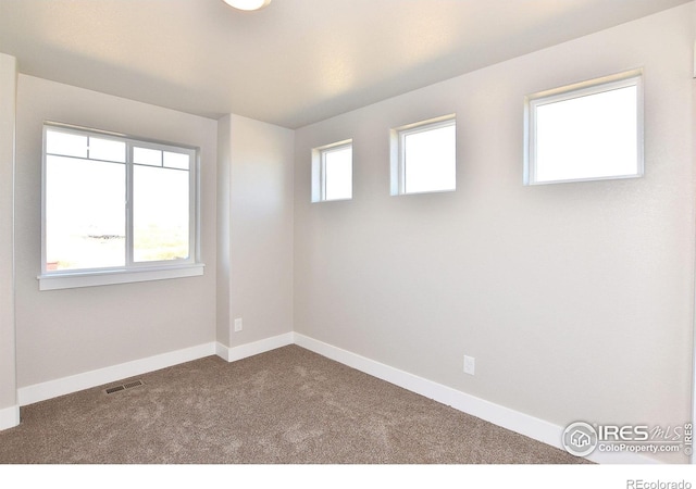 unfurnished room featuring dark carpet and baseboards