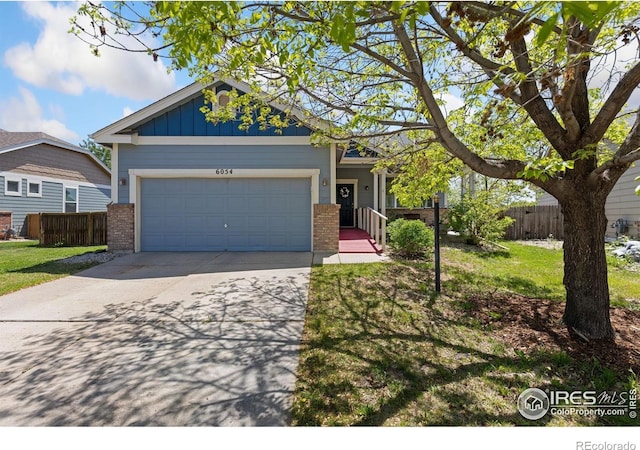 6054 Ulysses Ave, Firestone, CO 80504 - view of front facade with brick siding, concrete driveway, an attached garage, and board and batten siding
