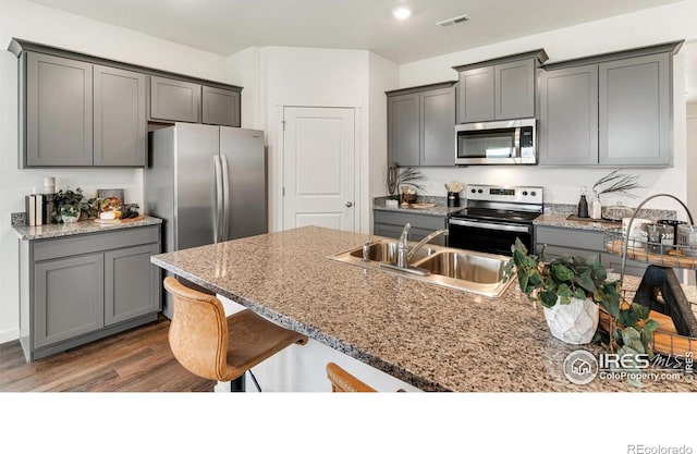 2727 73rd Ave, Greeley, CO 80634 - kitchen featuring stainless steel appliances, a sink, a kitchen bar, dark wood-type flooring, and gray cabinets