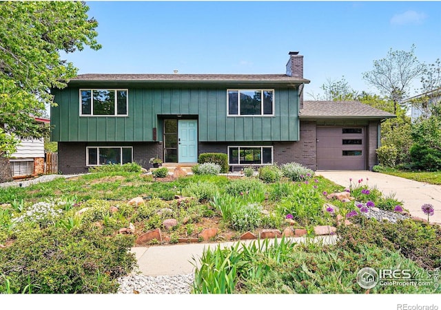 1350 Lehigh St, Boulder, CO 80305 - raised ranch featuring a chimney, a garage, driveway, and board and batten siding