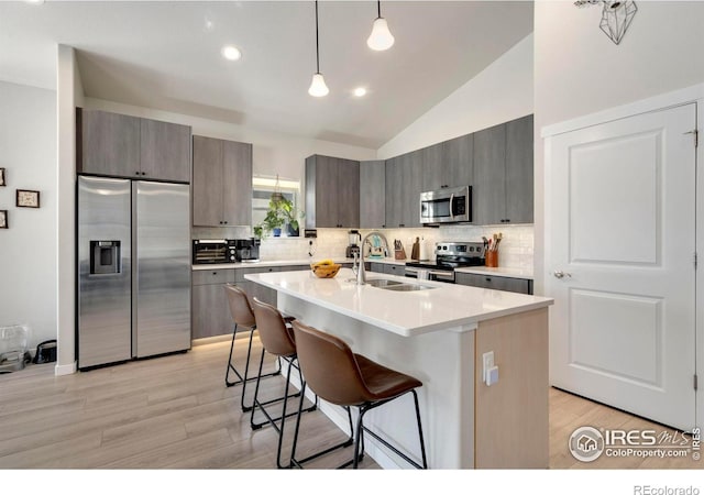 3593 Taylor Walker St, Loveland, CO 80537 - kitchen with appliances with stainless steel finishes, a sink, light wood finished floors, a breakfast bar area, and lofted ceiling