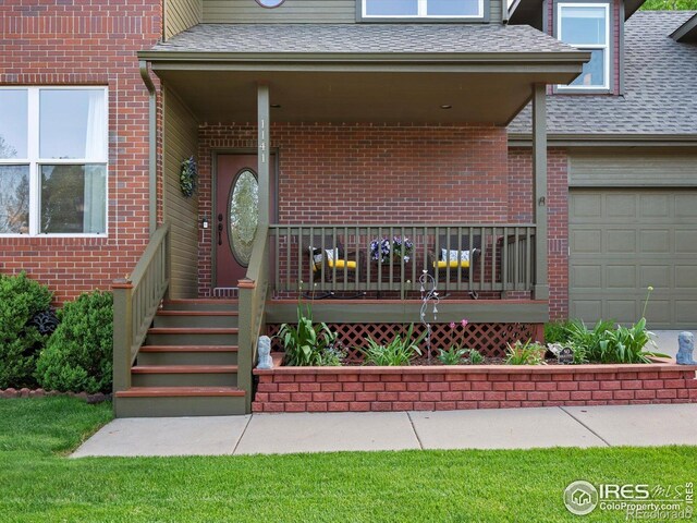 doorway to property with a porch, a shingled roof, brick siding, and a garage