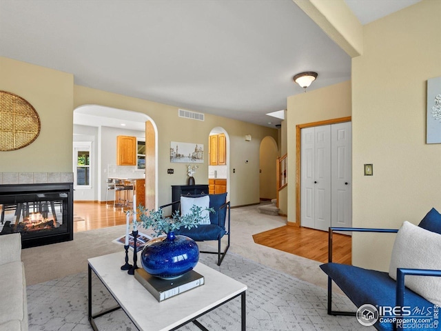 living area featuring arched walkways, light colored carpet, and a multi sided fireplace