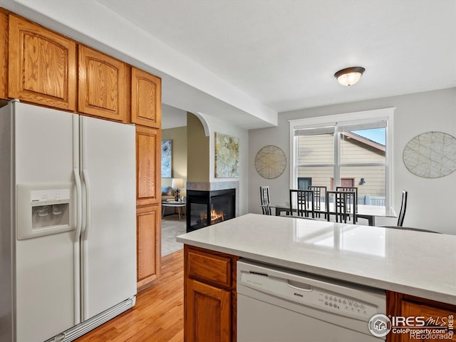 kitchen featuring white appliances, light wood-style floors, arched walkways, and light countertops