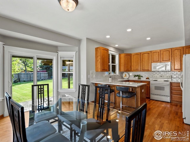 kitchen with white appliances, decorative backsplash, light countertops, a peninsula, and recessed lighting