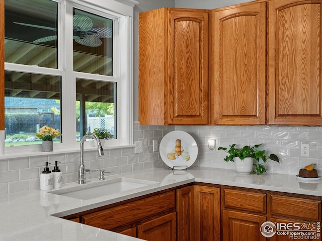 kitchen featuring a sink, tasteful backsplash, brown cabinets, and light countertops
