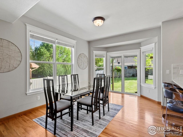 dining space featuring light wood-type flooring and baseboards