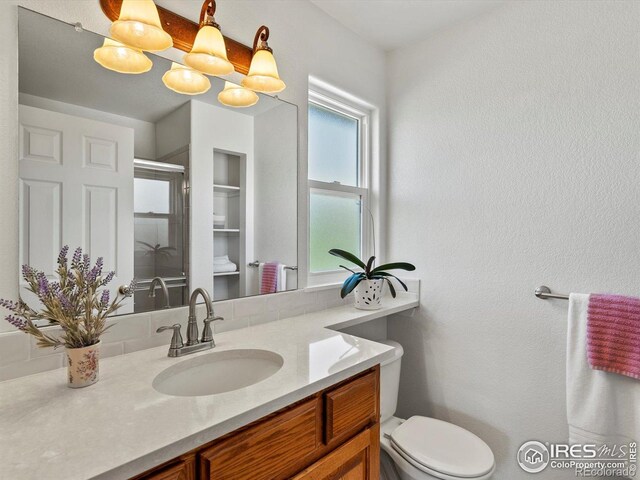 full bathroom featuring a stall shower, vanity, and toilet