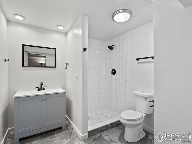 bathroom featuring baseboards, marble finish floors, toilet, tiled shower, and vanity