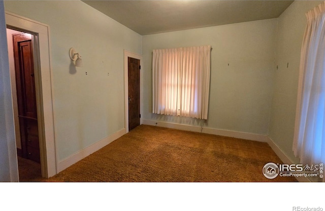 spare room featuring carpet and baseboards