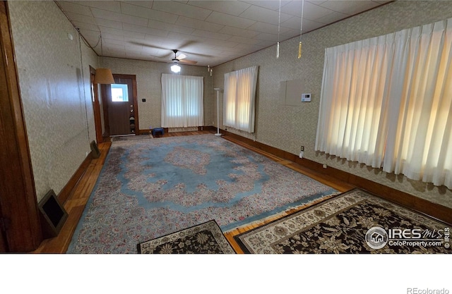 foyer featuring wallpapered walls, wood finished floors, and a ceiling fan