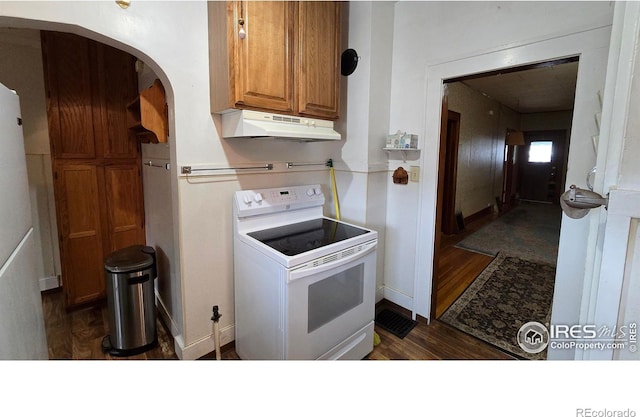 kitchen featuring white range with electric cooktop, under cabinet range hood, dark wood-type flooring, arched walkways, and brown cabinetry