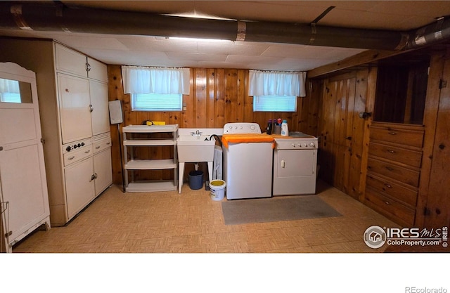 laundry room with wood walls, independent washer and dryer, and light flooring
