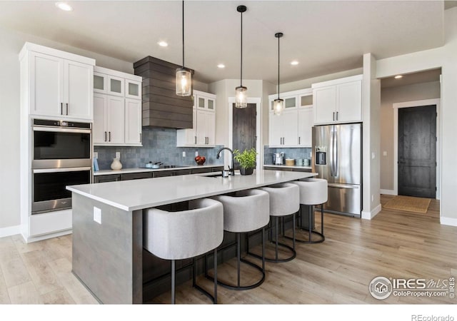 1721 Brightwater Dr, Fort Collins, CO 80524 - kitchen featuring stainless steel appliances, custom range hood, recessed lighting, decorative backsplash, and a center island with sink