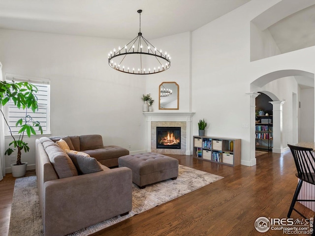 950 Sumner Way, Erie, CO 80516 - living room with arched walkways, wood finished floors, a tile fireplace, a high ceiling, and ornate columns