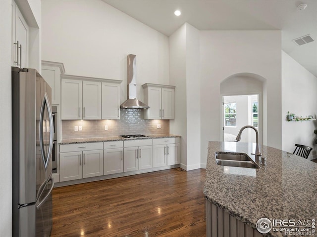 950 Sumner Way, Erie, CO 80516 - kitchen featuring a sink, appliances with stainless steel finishes, wall chimney exhaust hood, arched walkways, and dark wood-style flooring