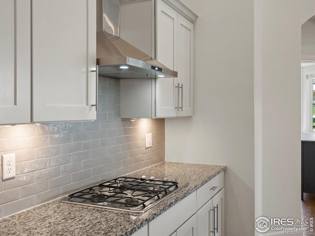 950 Sumner Way, Erie, CO 80516 - kitchen with wall chimney exhaust hood, stainless steel gas stovetop, tasteful backsplash, white cabinetry, and light stone counters