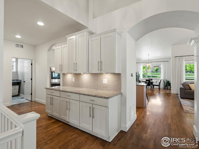 950 Sumner Way, Erie, CO 80516 - kitchen featuring arched walkways, dark wood finished floors, decorative backsplash, recessed lighting, and baseboards