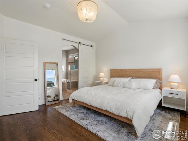 950 Sumner Way, Erie, CO 80516 - bedroom featuring a barn door, arched walkways, vaulted ceiling, wood finished floors, and connected bathroom