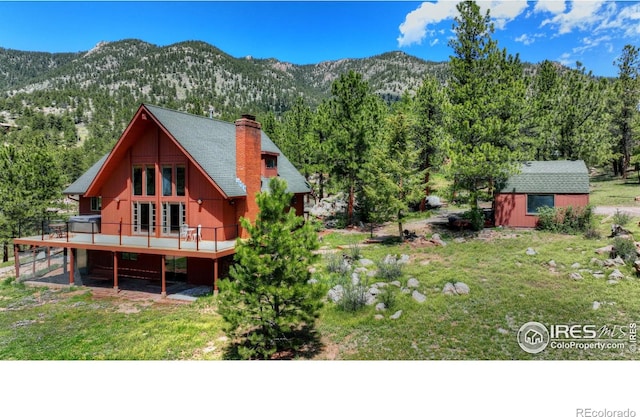 40 Hopi Ct, Lyons, CO 80540 - back of house featuring a deck with mountain view, a chimney, a wooded view, and a yard