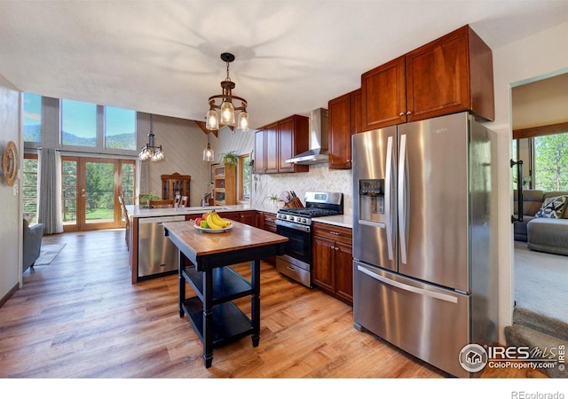 40 Hopi Ct, Lyons, CO 80540 - kitchen with appliances with stainless steel finishes, wall chimney exhaust hood, a peninsula, a sink, and light wood-style flooring