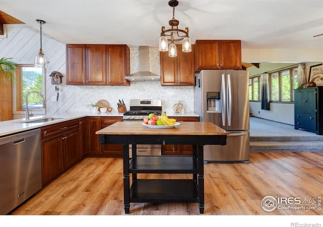40 Hopi Ct, Lyons, CO 80540 - kitchen with appliances with stainless steel finishes, wall chimney exhaust hood, a sink, light wood finished floors, and hanging light fixtures