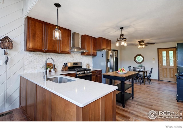 40 Hopi Ct, Lyons, CO 80540 - kitchen featuring stainless steel appliances, wall chimney range hood, a sink, light countertops, and decorative light fixtures