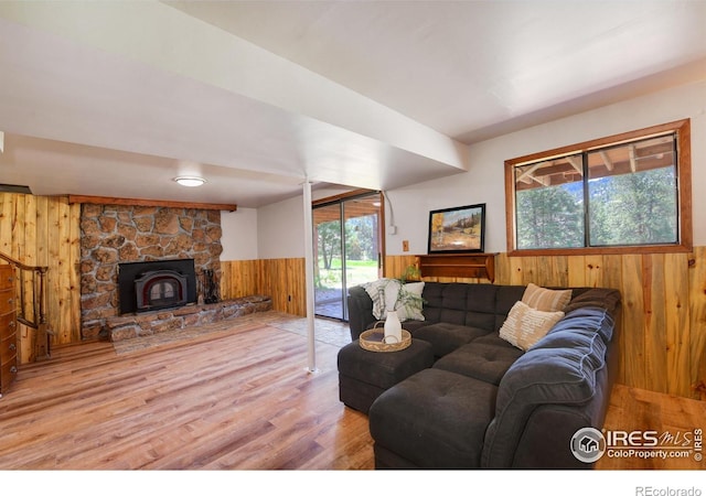 40 Hopi Ct, Lyons, CO 80540 - living area featuring wooden walls, healthy amount of natural light, wood finished floors, wainscoting, and a stone fireplace