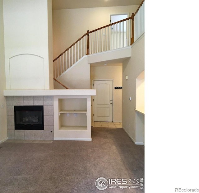 6608 W 3rd St Unit 35-58, Greeley, CO 80634 - unfurnished living room featuring carpet floors, baseboards, a fireplace, stairs, and a towering ceiling