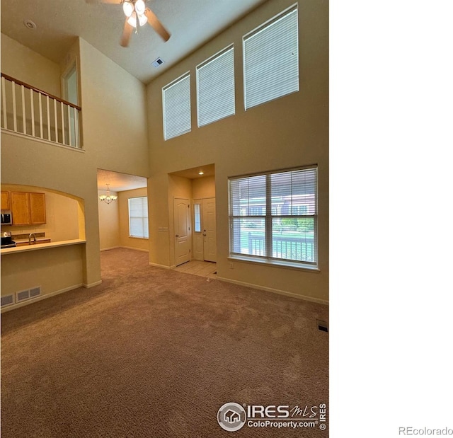 6608 W 3rd St Unit 35-58, Greeley, CO 80634 - unfurnished living room with ceiling fan, carpet flooring, a chandelier, baseboards, and a towering ceiling