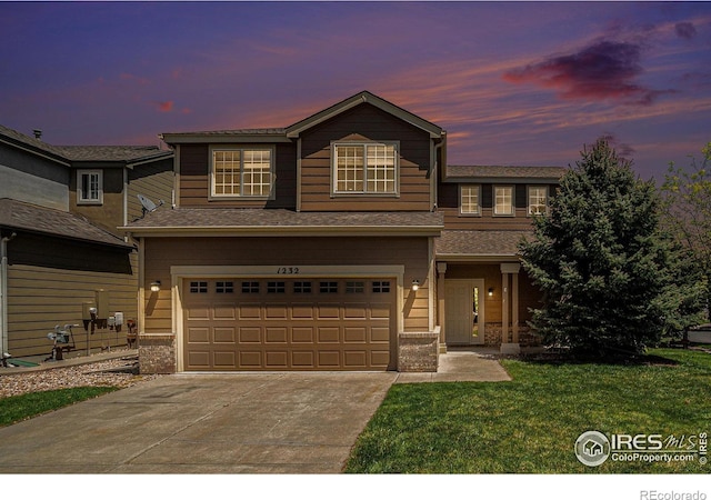 traditional-style home featuring an attached garage, driveway, and a yard
