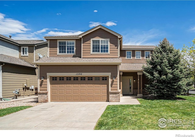 view of front of property with an attached garage, concrete driveway, a front yard, and roof with shingles