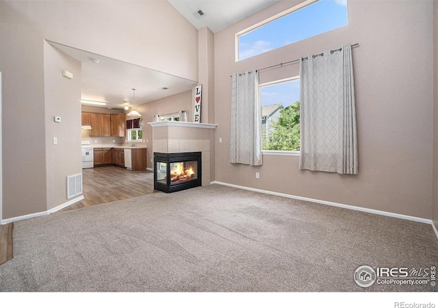 living room with light colored carpet, baseboards, a fireplace, and a high ceiling