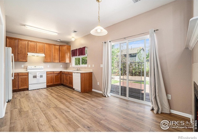 kitchen with white appliances, light wood-style flooring, brown cabinetry, and light countertops