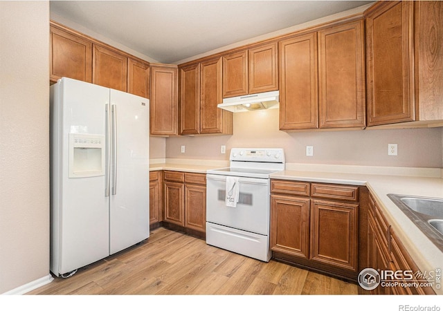kitchen featuring white appliances, under cabinet range hood, light wood-style flooring, and brown cabinetry