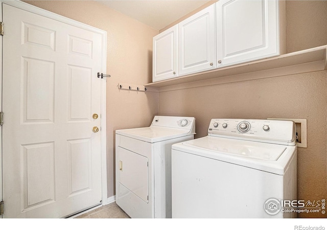 clothes washing area featuring washing machine and clothes dryer and cabinet space