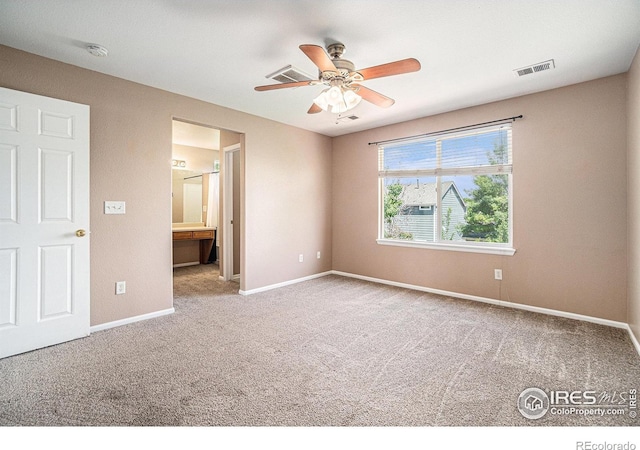 unfurnished bedroom featuring carpet, baseboards, ensuite bath, and a ceiling fan
