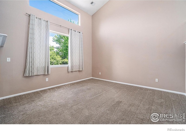 carpeted spare room featuring vaulted ceiling and baseboards