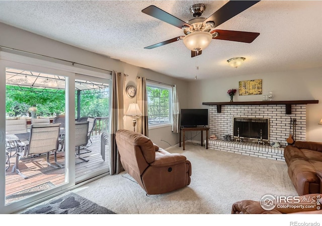 carpeted living room with a textured ceiling, a ceiling fan, and a brick fireplace