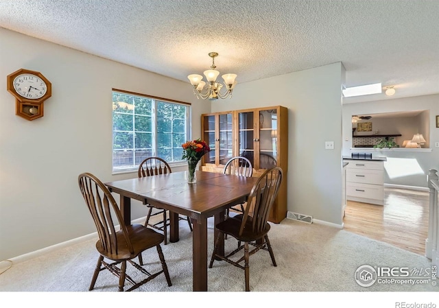 dining room with light carpet, a chandelier, a textured ceiling, french doors, and baseboards