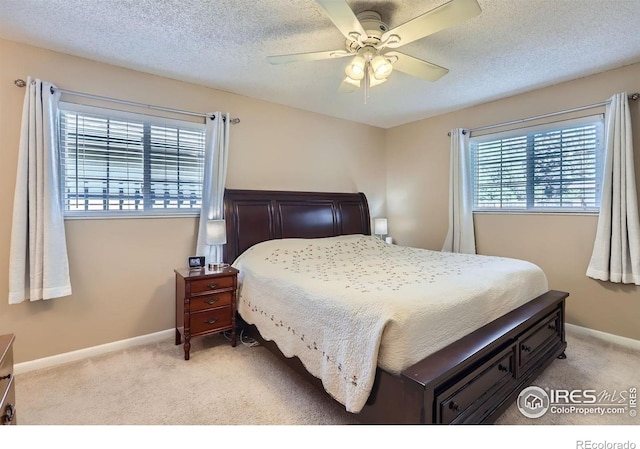 bedroom with light carpet, ceiling fan, baseboards, and a textured ceiling