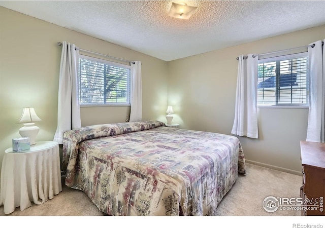 bedroom featuring light colored carpet, a textured ceiling, and baseboards