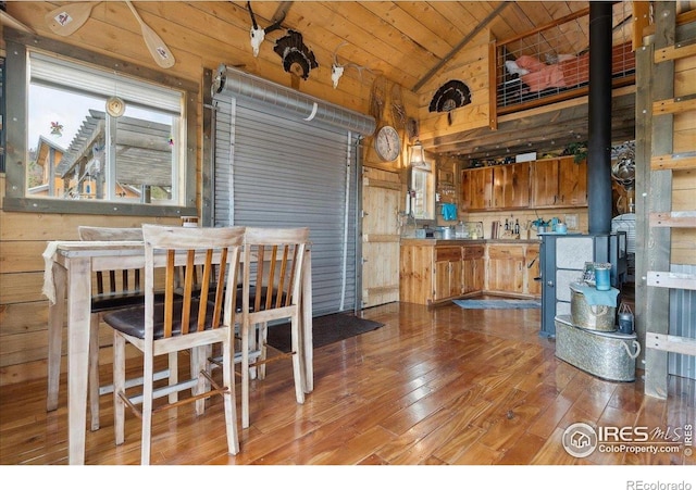 1095 Spruce Mountain Dr, Drake, CO 80515 - dining area featuring vaulted ceiling, hardwood / wood-style flooring, a wood stove, wooden ceiling, and wood walls