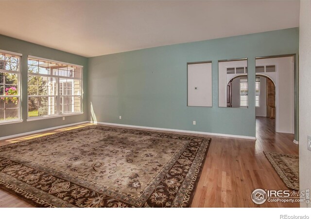 2409 Rock Creek Dr, Fort Collins, CO 80528 - spare room with wood finished floors, arched walkways, and baseboards