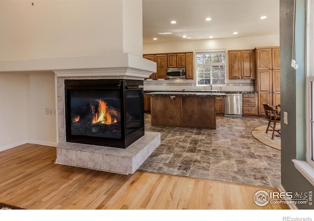 2409 Rock Creek Dr, Fort Collins, CO 80528 - kitchen featuring appliances with stainless steel finishes, a kitchen island, recessed lighting, a tile fireplace, and brown cabinetry