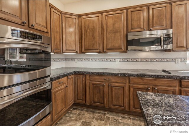 2409 Rock Creek Dr, Fort Collins, CO 80528 - kitchen with stainless steel appliances, dark stone finish floors, backsplash, brown cabinets, and dark stone countertops
