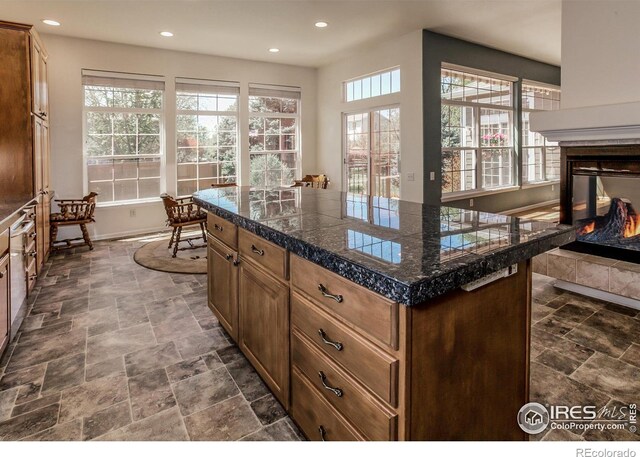 2409 Rock Creek Dr, Fort Collins, CO 80528 - kitchen featuring tile counters, a multi sided fireplace, dark stone finish floors, recessed lighting, and baseboards