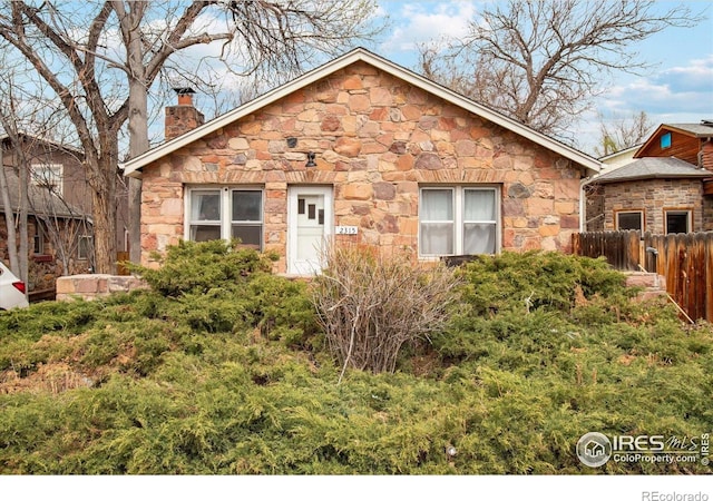 2315 Spruce St, Boulder, CO 80302 - view of front of home with stone siding, fence, and a chimney