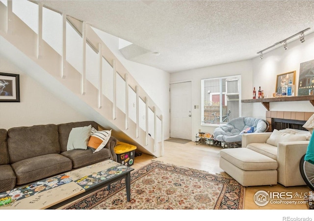 2315 Spruce St, Boulder, CO 80302 - living area featuring track lighting, wood finished floors, stairs, a textured ceiling, and a tile fireplace